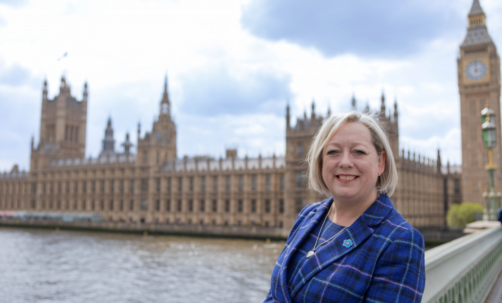 Jackie Doyle-Price MP stood on Westminster Bridge in front of the Houses of Parliament building